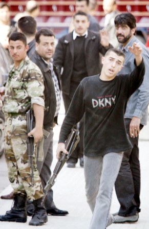احد افراد المخابرات السورية يحمل سلاحه وينهر الصحفيين الذين يقومون بتغطية انسحاب المخابرات السورية في بيروت امس