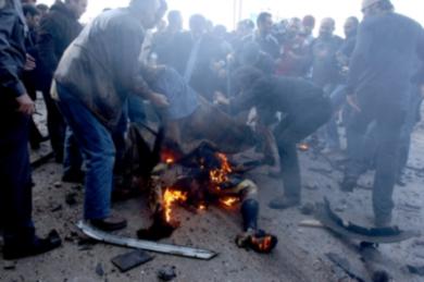 جثة الشهيد الحريري وهي تحترق جراء الانفجار الكبير والمواطنون يقومون بتغطيتها 