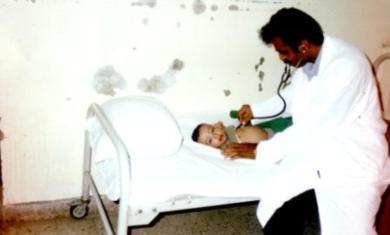 احد الاطباء اثناء الكشف على طفل مريض في قسم الاطفال