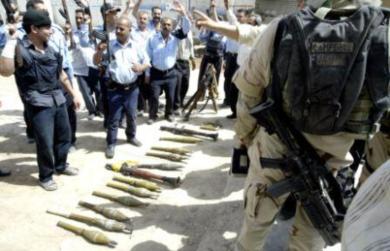 تجمعت الشرطة العراقية والجنود الامريكيون امام الاسلحة التي استوليت عليها من المتمردين