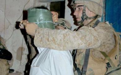 جندي امريكي يقوم بعصب عيني معتقل عراقي