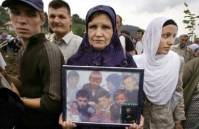 امراة بوسنية تحمل صور لاطفال مذبحة سربرنيتشا عام1995م
