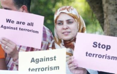 امراة مغربية تحمل لافتة كتب عليها "ضد الارهاب" واخر كلنا ضد الارهارب