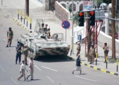 مواطنون يسيرون أمام دبابة في أحد شوارع صنعاء أمس