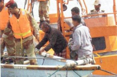 الصيادون الثلاثة عند نزولهم من السفينة الحربية ويظهر جزء من قاربهم الذي تم ربطه ونقله بالسفينة
