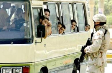 سائق باص يتحدث مع جندي أميركي يراقب احدى نقاط التفتيش في بغداد أمس