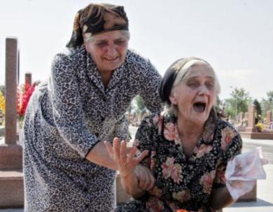 امرأتان مسنتان تبكيان امام قبر اقاربهم