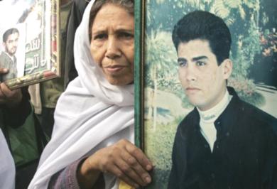 امرأة فلسطينية تحمل صور لابنها المعتقل في السجون الاسرائيلية ...