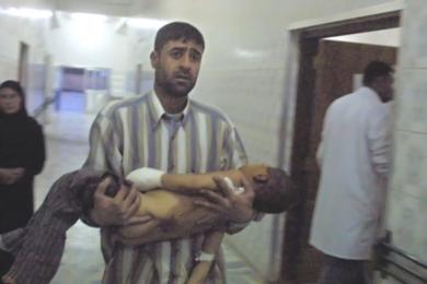 رجل عراقي يحمل طفلاً مصاب في احدى المستشفيات العراقية