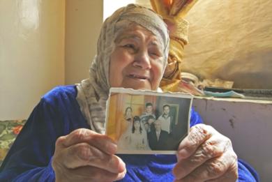 امرأة فلسطينية مسنة تعرض صورة لاقاربها المعتقلين 