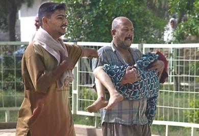 رجل عراقي يحمل طفلة اصيبت في هجوم يوم امس