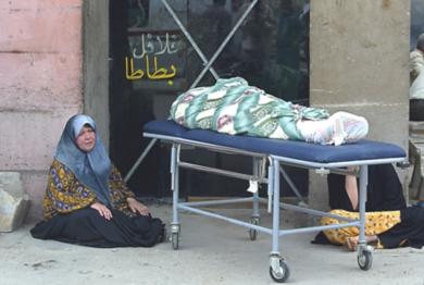 امرأة عراقية تجلس امام جثة احدى قريباتها
