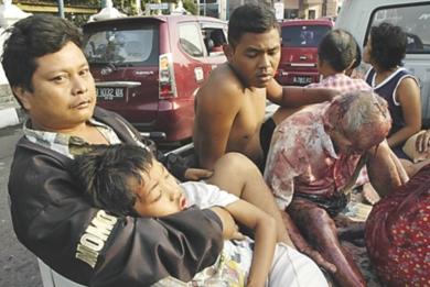 اندونيسي يحمل ابنه الذي قتل في زلزال أمس