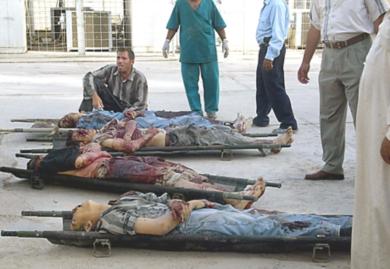 عراقي يجلس امام جثث عمال قتلوا يوم أمس في هجمات متفرقة في العراق