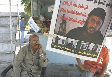 عراقي جالس وخلفه صورة زعيم تنظيم القاعدة في العراق ابو مصعب الزرقاوي
