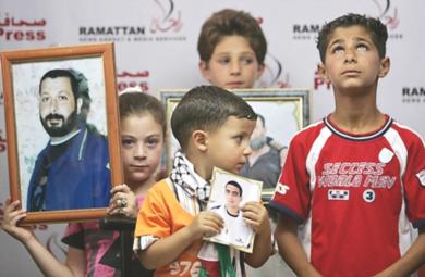 أطفال الأسرى الفلسطينيين يحملون صور قديمة لأبائهم