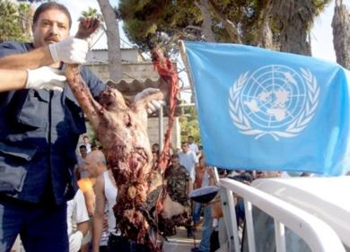 عامل من الأمم المتحدة يحمل جثة إحدى الضحايا البالغ عددهم 20 بينهم 15 طفلاً خارج بوابة الامم المتحدة بعد قصف مروحية اسرائيلية سيارة فان بصاروخ جنوب مدينة صور أمس