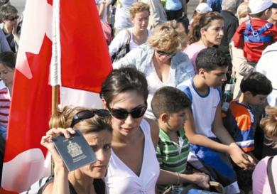 امرأة تحمل الجنسية اللبنانية الكندية المزدوجة تظهر جوازها الكندي بينما ينتظر المئات قرب مرفأ بيروت لإجلائهم أمس