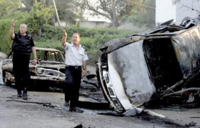 شرطيان اسرائيليان يقفان بجانب سيارتين احترقتا بعد قصف صاروخي لحزب الله في مدينة نهاريا شمال اسرائيل