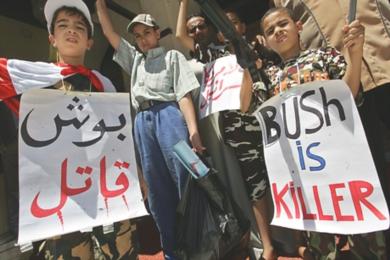 اطفال يحملون لافتات كتبت عليها "بوش قاتل"
