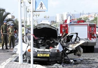 رجال أمن اسرائيليون يقفون أمام سيارة أصابها صاروخ لحزب الله في مدينة نهاريا أمس