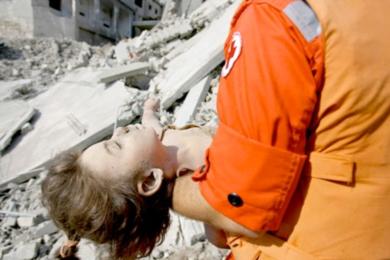 عنصر من الصليب الأحمر يحمل جثة فتاة قضت في القصف على ملجأ في قانا