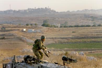 جندي إسرائيلي يجري محاولا الاحتماء لتفادي نيران مقاتلي حزب الله في جنوب لبنان أمس