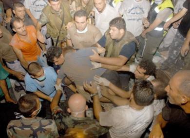 مسعفون وجنود وسكان محليون يرفعون جثة قتيل بعد قصف إسرائيل للشياح بضاحية بيروت الجنوبية أمس