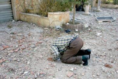 مواطن لبناني يسجد مقبلاً الأرض أمام منزله المصاب بأضرار في قرية الجندرية في جنوب لبنان أمس بعد عودته من بيروت