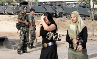 سيدتان لبنانيتان تسيران أمس أمام جنود الجيش اللبناني بمدينة صور بعد عودة الحياة الطبيعية تدريجياً وببطء إلى جنوب لبنان