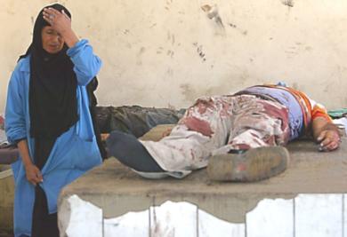 امرأة عراقية تجلس امام جثة احد اقاربها الذي قتل في الانفجار