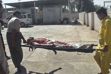 عراقيان يحملان جثة احد القتلى