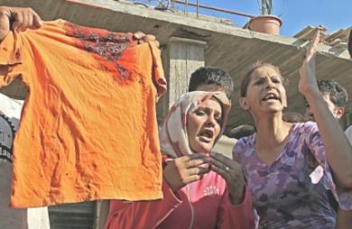 امرأة لبنانية تحمل قميصا قطنيا لفتى اصيب بطلاقة نارية 