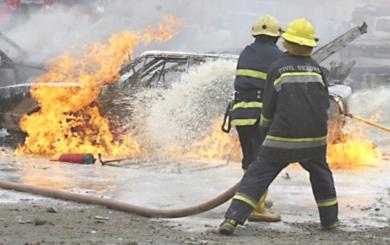 عمال الاطفاء يقومون بإخماد الحريق في احدى السيارات المتضررة