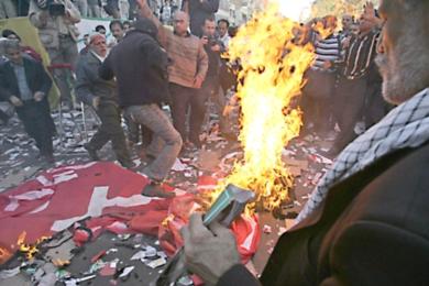 محتجون يحرقون العلم الامريكي امام السفارة الامريكية السابقة