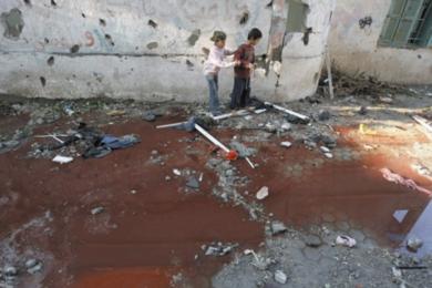 طفلان فلسطينان ينظران إلى بركة من المياه المخلوطة بدماء الفلسطينيين بعد غارة إسرائيلية على بيت حانون أمس