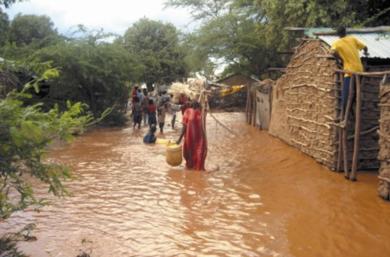 سكان محليون يخوضون المياه الفائضة من نهر تانا بمنطقة جاريسا الكينية على الحدود مع الصومال أمس الأول