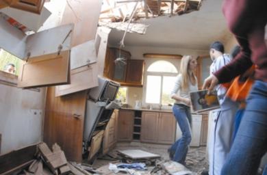 أفراد أسرة إسرائيلية يتفقدون الأضرار التي لحقت بمنزلهم إثر سقوط أحد صواريخ القسام عليه في بلدة سديروت جنوب إسرائيل أمس بعد تهديد منظمة الجهاد لاسرائيل بضرورة قيام دولة فلسطينية على حدود قبل 1967