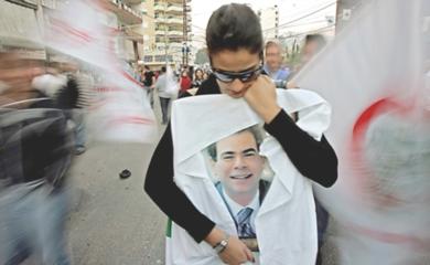 امرأة لبنانية تحمل صور الوزير المغتال بيار الجميل امام مكان وقوع الاعتداء عليه