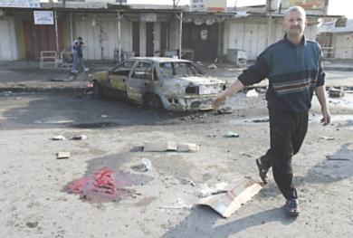 عراقي يمر من امام بقع الدماء .. بعد عملية انتحارية بسيارة مفخخة