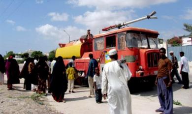 صوماليون يتفقدون سيارة إطفاء تعرضت للقصف الجوي الاثيوبي بمطار مقدشو أمس