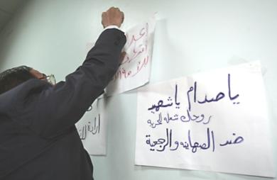 محامي مصري يعلق ملصقات في الحائط تندد بالاعدام الذي راح ضحيتها صدام حسين