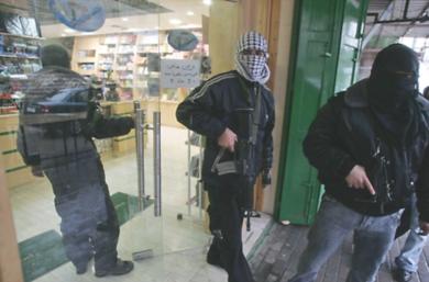 فلسطينيون ملثمون يقومون بإغلاق احد المحلات التجارية في الخليل