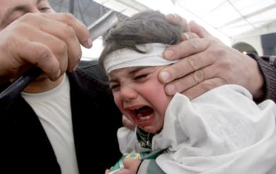 رضيع يبكي في بلدة النبطية اللبنانية بينما يستعد والده لقطع فروة رأسه لإسالة الدم احتفالاً بعاشوراء يوم أمس