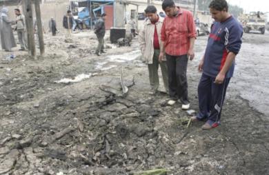 مواطنون عراقيون ينظرون إلى حفرة سببها الانفجار