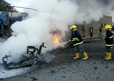 عمال الأطفاء يقومون بإخماد احد الحرائق في احد السيارات المتضررة
