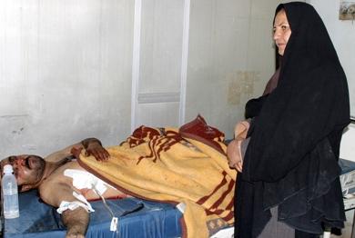 امرأة عراقية تقف امام زوجها وهو طريح الفراش في المستشفى بعد اصابته بأجزاء جسمه أمس
