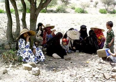 نساء وأطفال يجلسون تحت شجرة إثر عمليات مداهمة البيوت