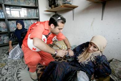 رجل الاسعاف يعالج امرأة فلسطينية في مخيم للاجئين أمس