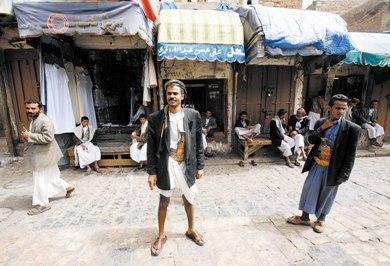 يمني يقف بزيه التقليدي أمام بعض المحلات التجارية بسوق الملح
